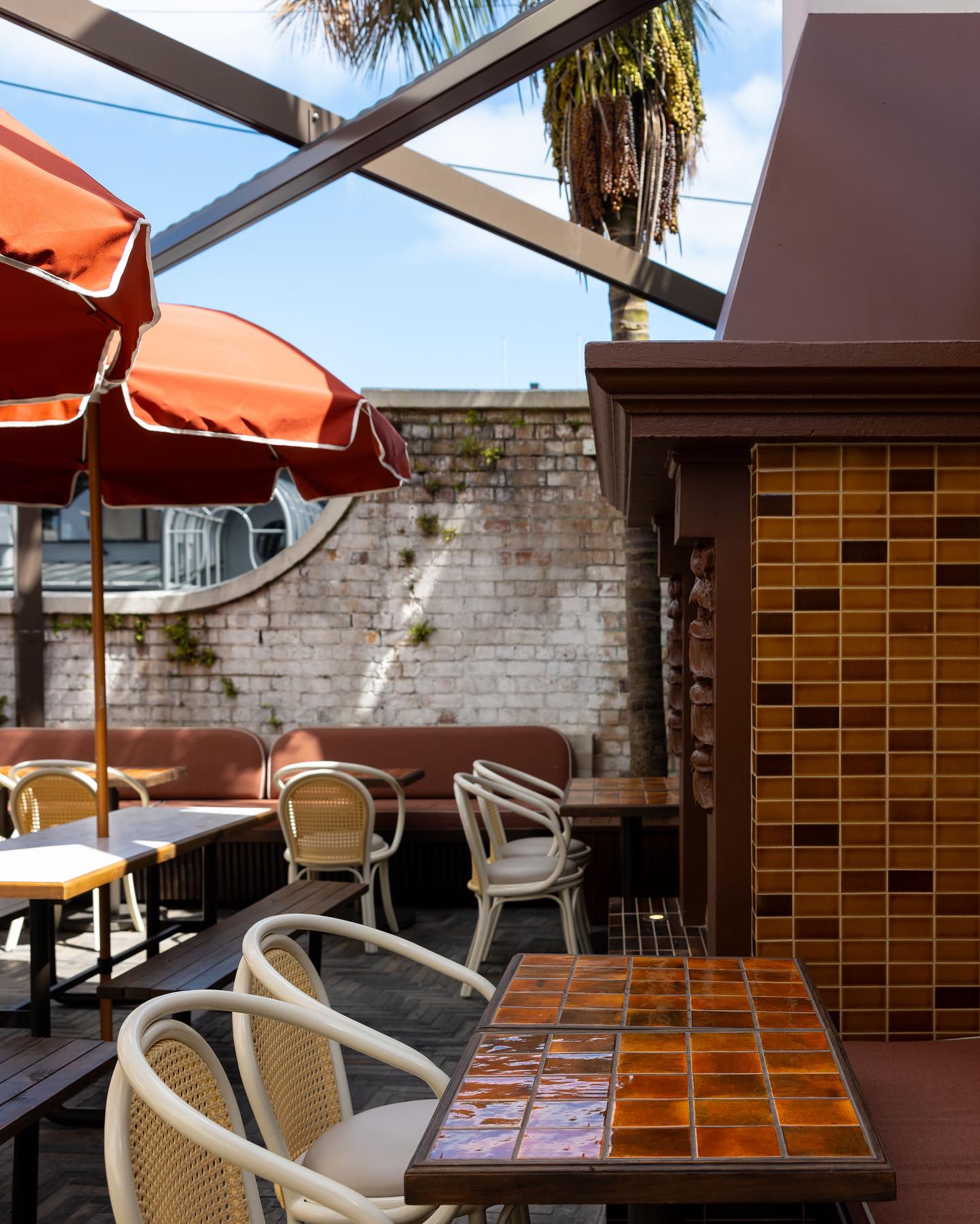 Curved white rattan cafe chairs with cane backrests at outdoor commercial dining tables
