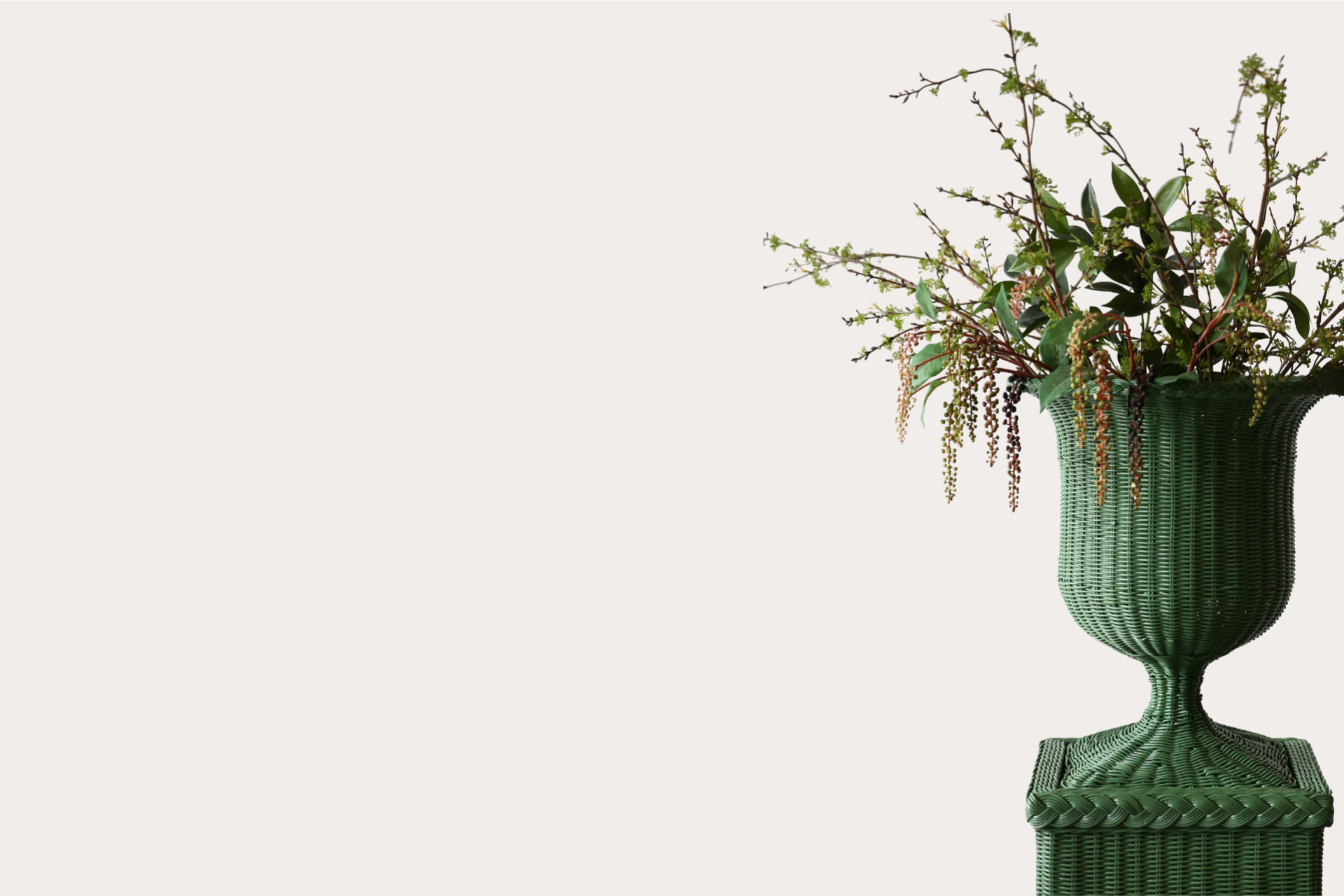 Tall green wicker pedestal vase with fluted body and natural foliage display