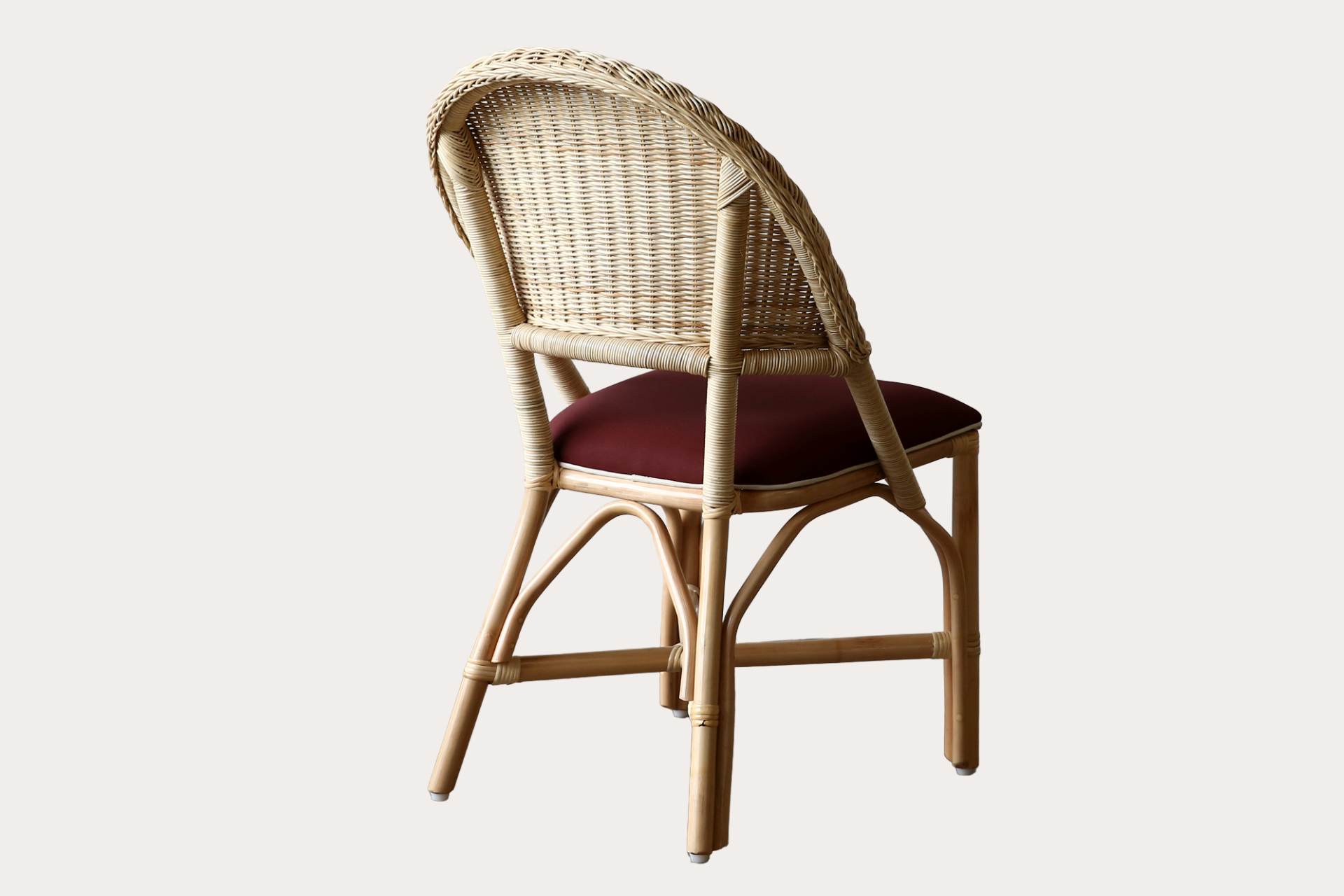 Drucker style Wicker chair with a red cushion on a white background. Made from rattan with natural cane weave on back rest.