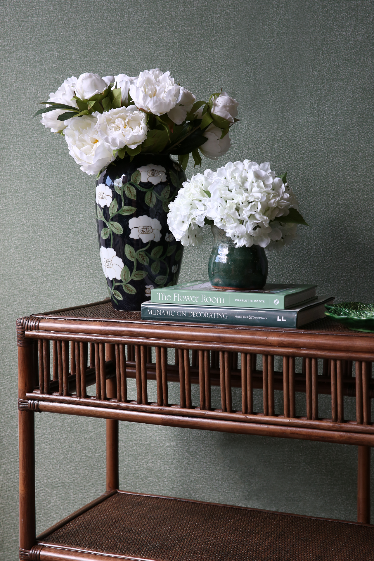 President console table in brown wash rattan with floral decor and hardcover design books
