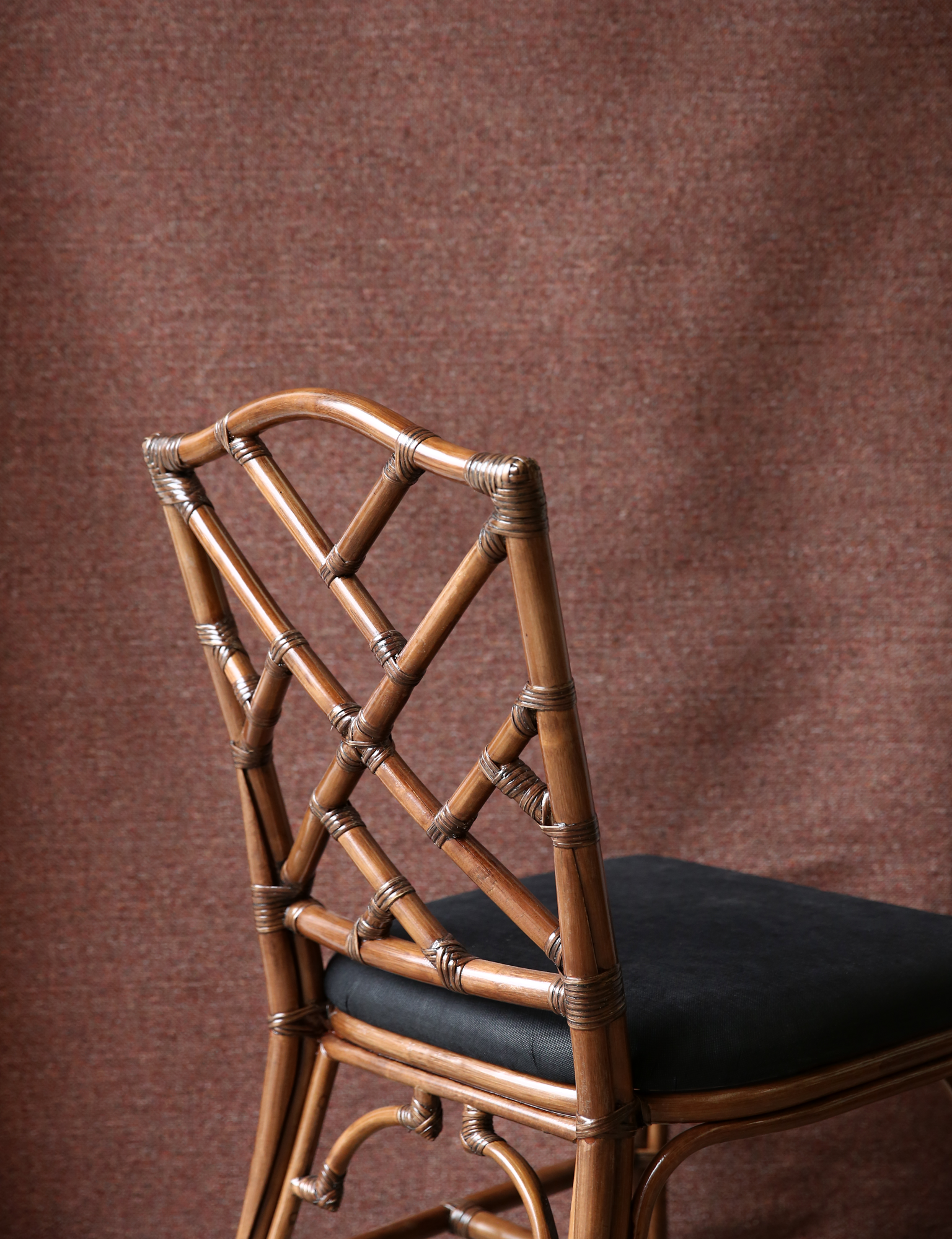 carved rattan dining chair with upholstered seats and brown washed frames in a chippendale style.