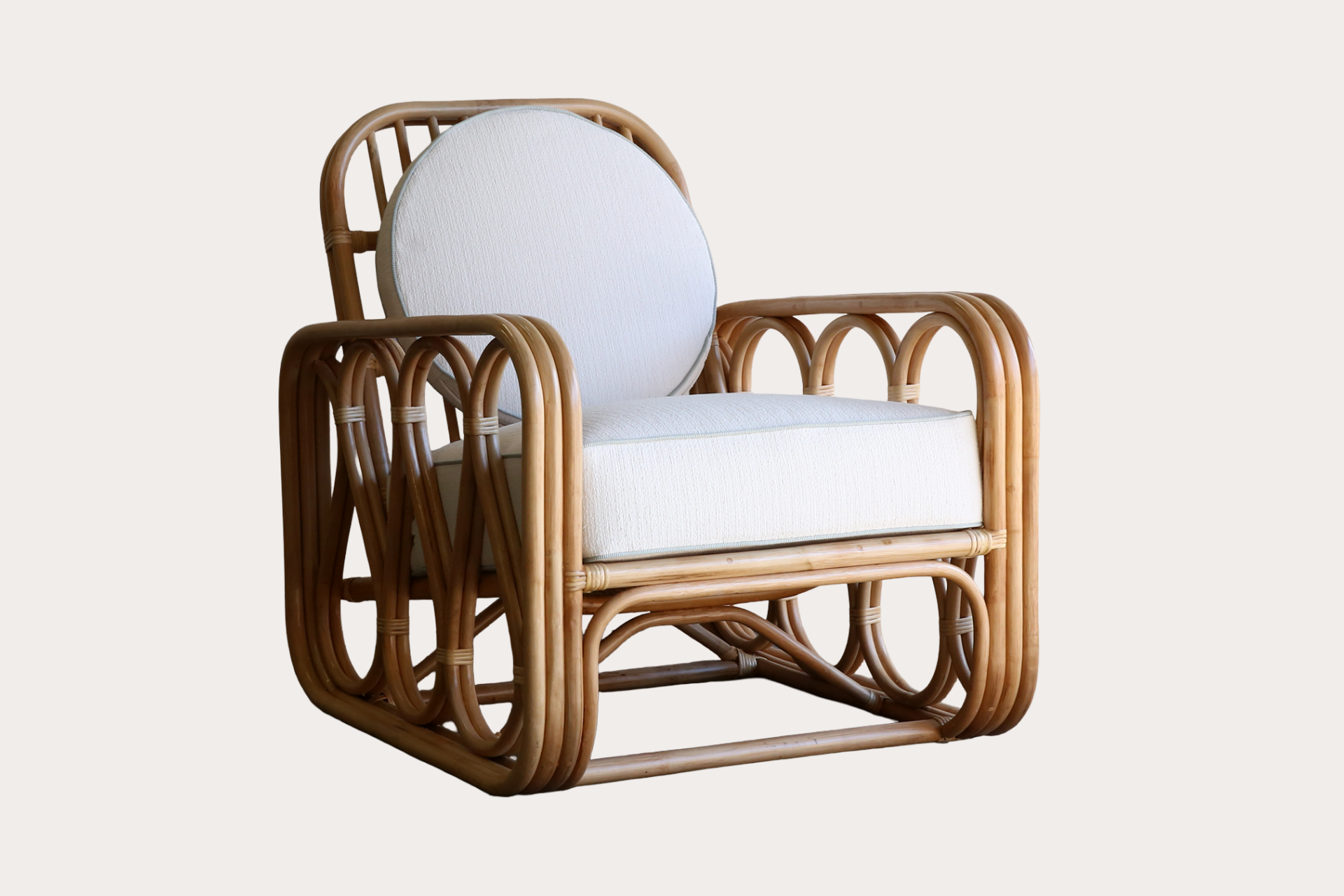 Wicker chair with white cushion on a light background