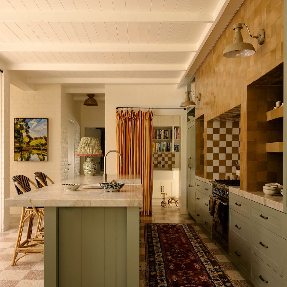 Handcrafted rattan counter stools in a custom residential kitchen with marble island and checkerboard tile backsplash